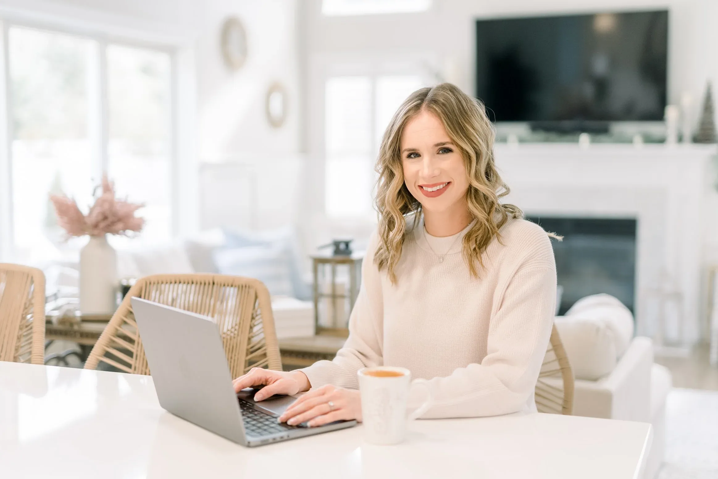Taylor Wilson smiling at her laptop in a bright living room